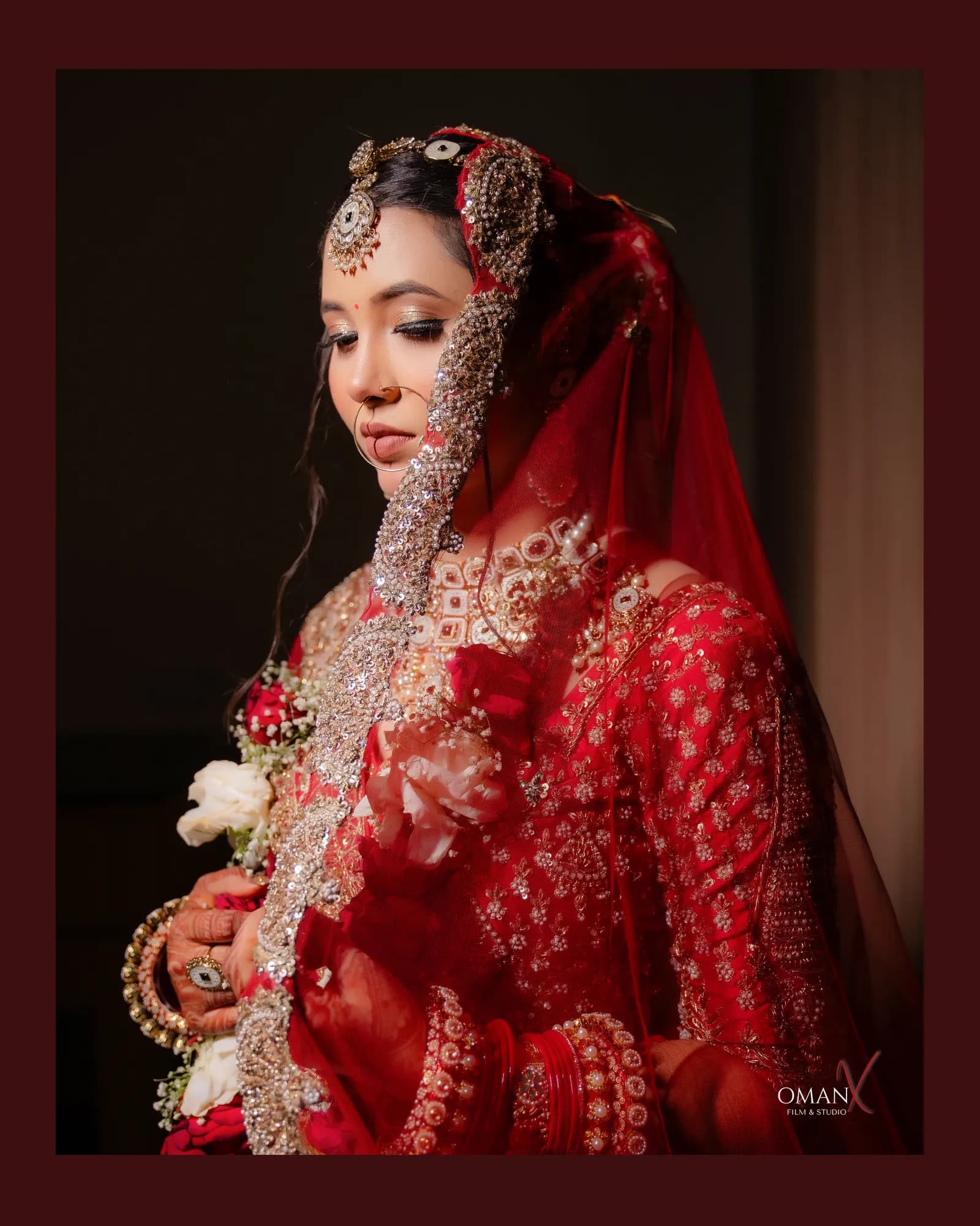 Indian bride in a red bridal outfit and traditional jewellery posing for an elegant wedding portrait